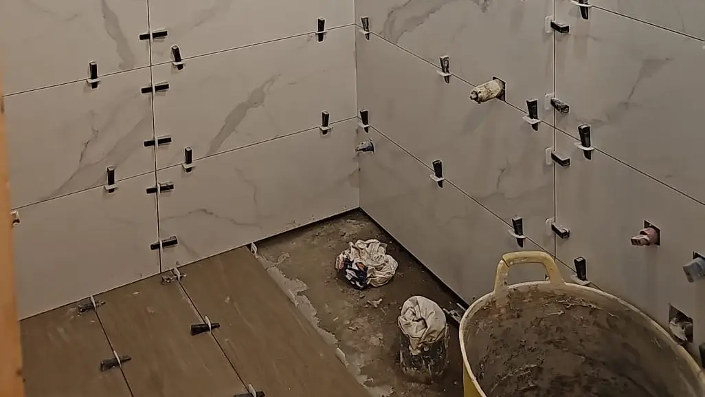Pared de baño con azulejos y crucetas de nivelación durante el alicatado