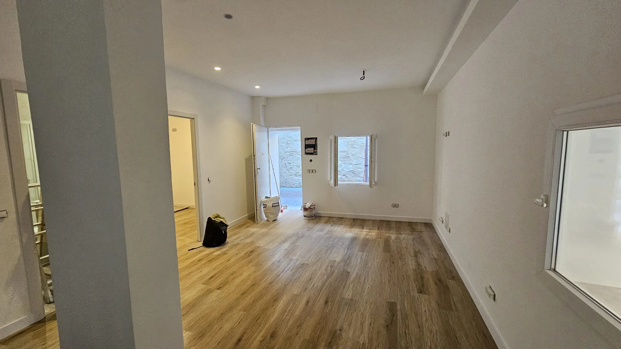 Salón reformado con suelo de madera y paredes blancas en una vivienda de Madrid
